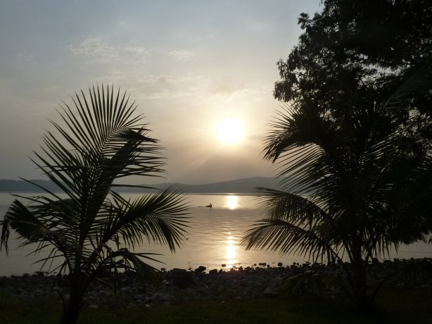 A fisherman checks his nets with the sun rising behind him.