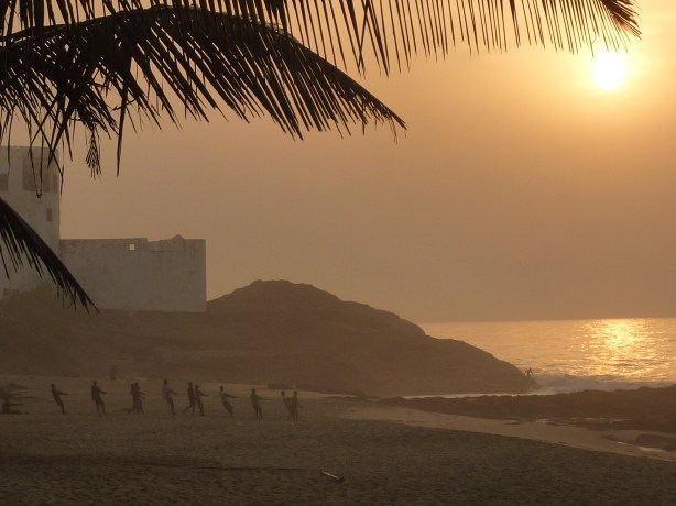 Men pull in their fishing nets at sunset (Elmina, Ghana)
