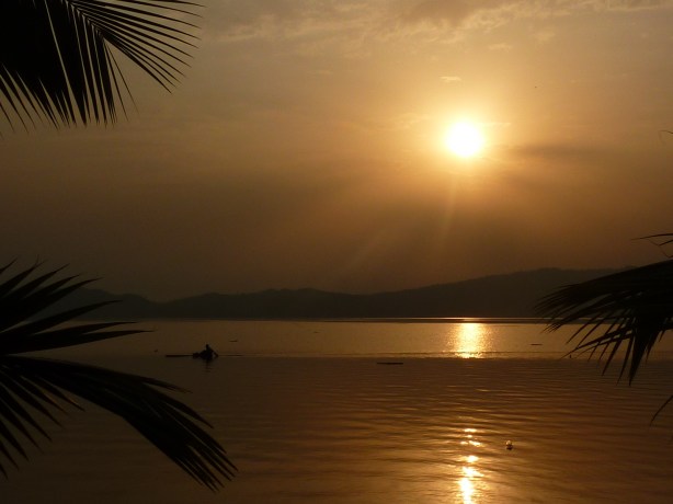 The sun is setting as a fisherman checks his nets for the last time in the day. (Lake Bosumtwi, Ghana)